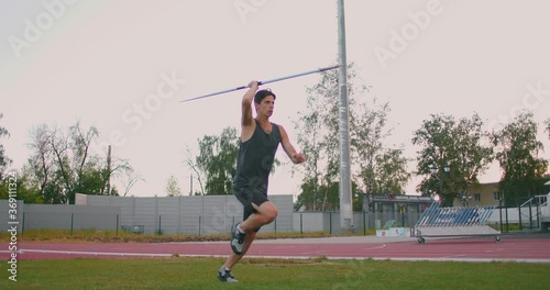 A male athlete throws javelins at a stadium in slow motion. Athletics javelin throw Olympic program