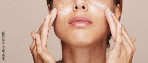 Woman portrait applying cream or moisturiser isolated