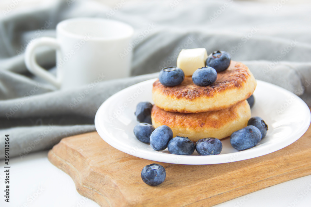 A healthy breakfast of pancakes, berries, butter, and honey.