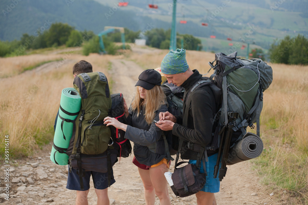 guys look at the route on the phone map and fasten their backpack guys look at the route on the phone map and fasten their backpack