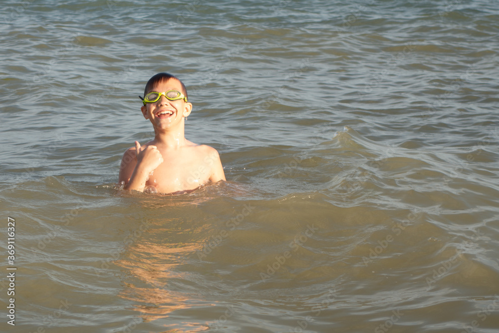 Boy 10 years old enjoys swimming in the coastal waves in the sea. Satisfied with the results of the swim.