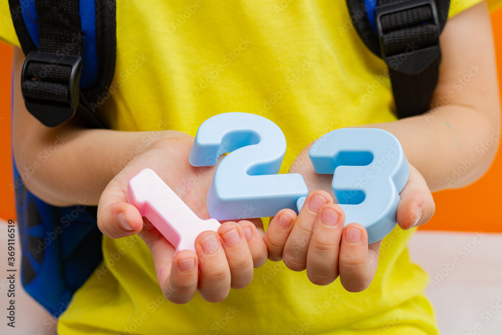 School child preschooler child holds numbers 1 2 3 close-up. Learning mathematics and counting in a playful way