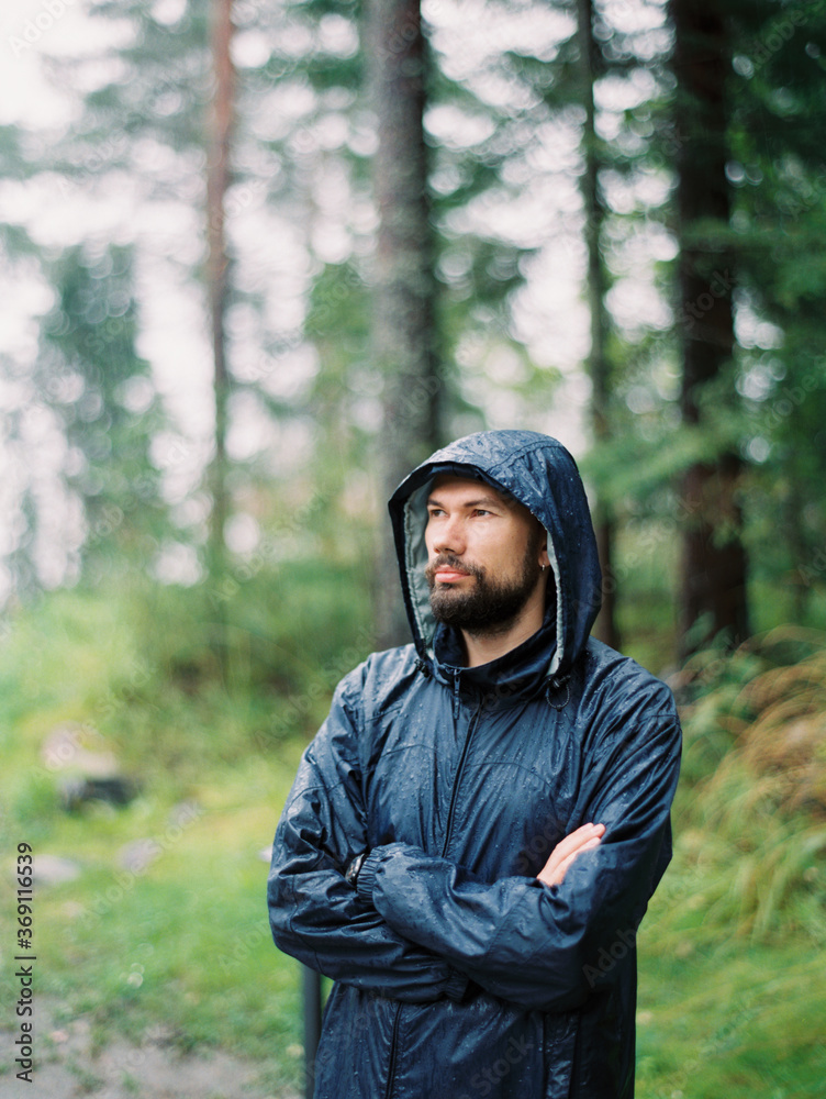 Man wearing coat staying under a rain in a forest Man wearing coat staying under a rain in a forest