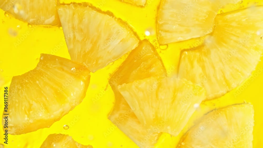 Super Slow Motion Shot of Pineapple Slices Falling into Water on Yellow Background at 1000fps. Super Slow Motion Shot of Pineapple Slices Falling into Water on Yellow Background at 1000fps.