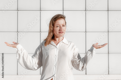 Young european indignant unsuspecting woman shrugs shoulders and spreads her arms to the sides of helplessness being unsure. I do not know how it hapened. Human face expressions and emotions. photo
