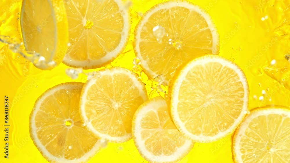 Super Slow Motion Shot of Lemon Slices Falling into Water on Yellow Background at 1000fps.