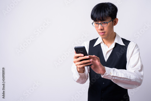 Portrait of young handsome Asian businessman using phone