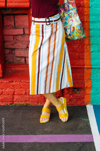 Woman in striped skirt and yellow flip flops