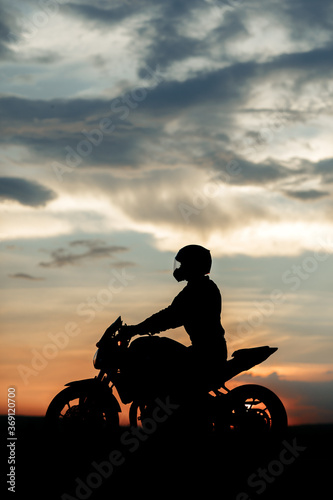 Fototapeta Silhouette photo of biker driving motorcycle in sunset on the on country road