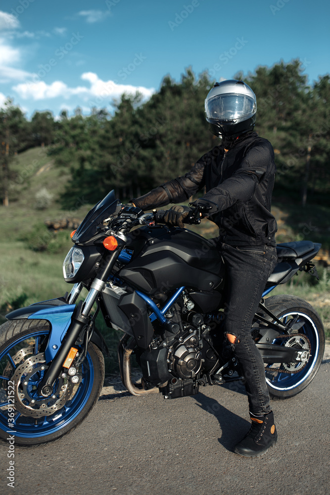 Photo of biker sitting on motorcycle in sunset on the country road. Photo of biker sitting on motorcycle in sunset on the country road.