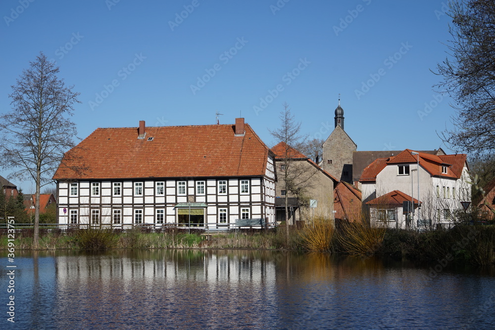 Spiegelung von Häusern im Wasser an einem Teich in einem Ort