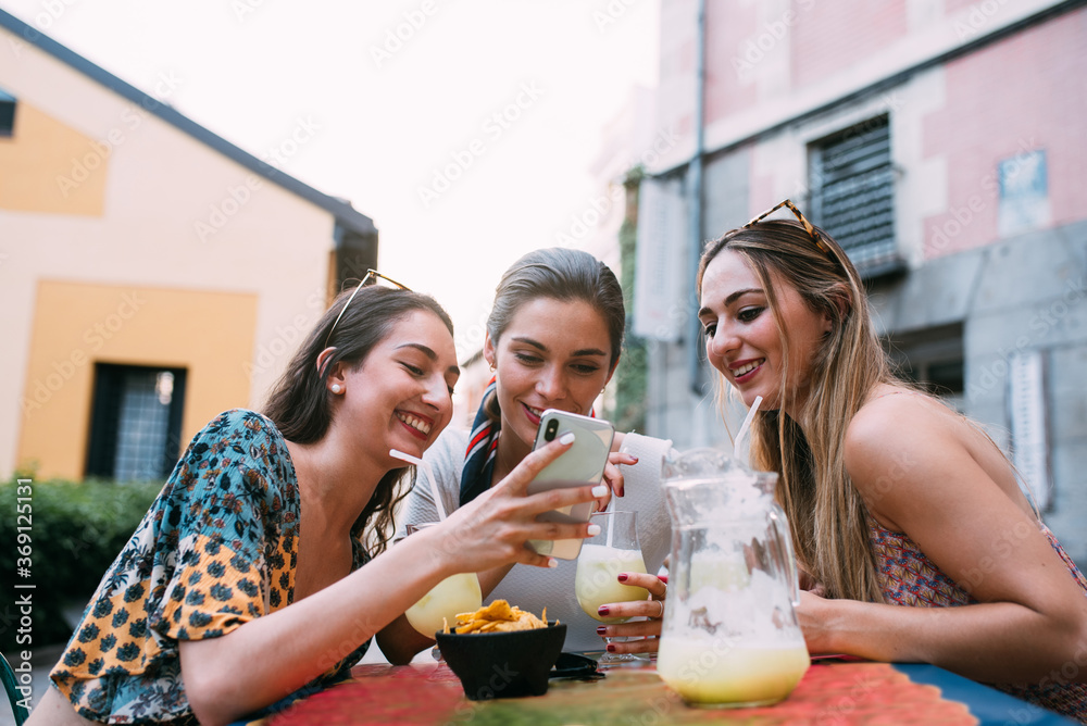 Happy Friends having lemonade drinks and using smartphone in a o Happy Friends having lemonade drinks and using smartphone in a o