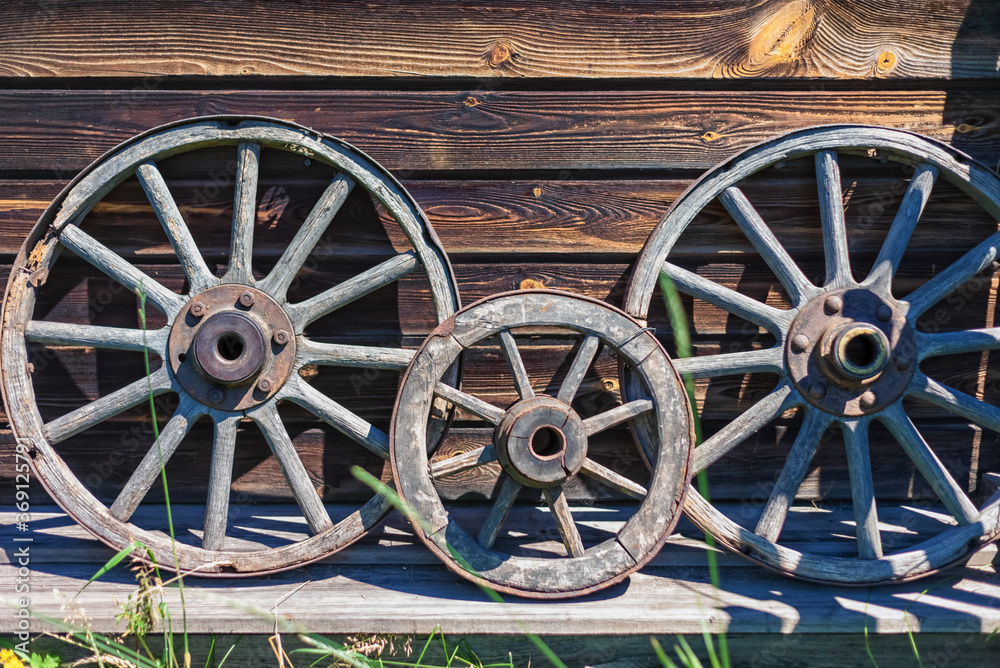 Vintage wooden cart wheels on the background of a wooden wall.