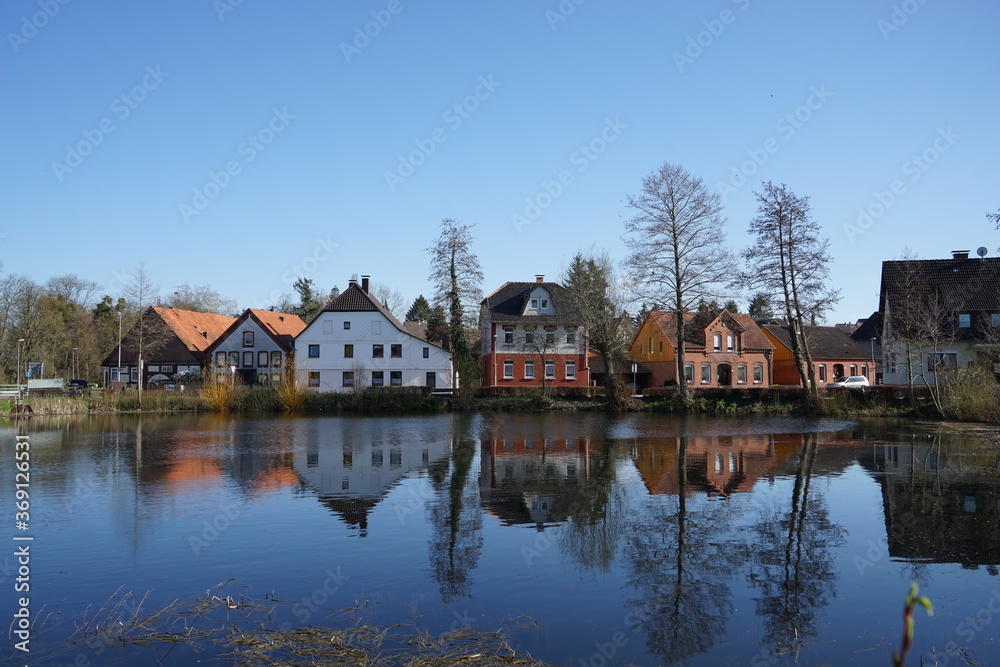 Spiegelung im Wasser an einem Teich mit Häusern