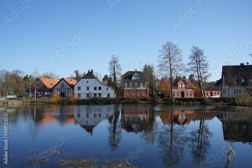 Spiegelung im Wasser an einem Teich mit Häusern © sturmschaden