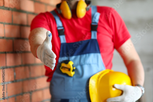 Builder at object holds out his hand for greeting