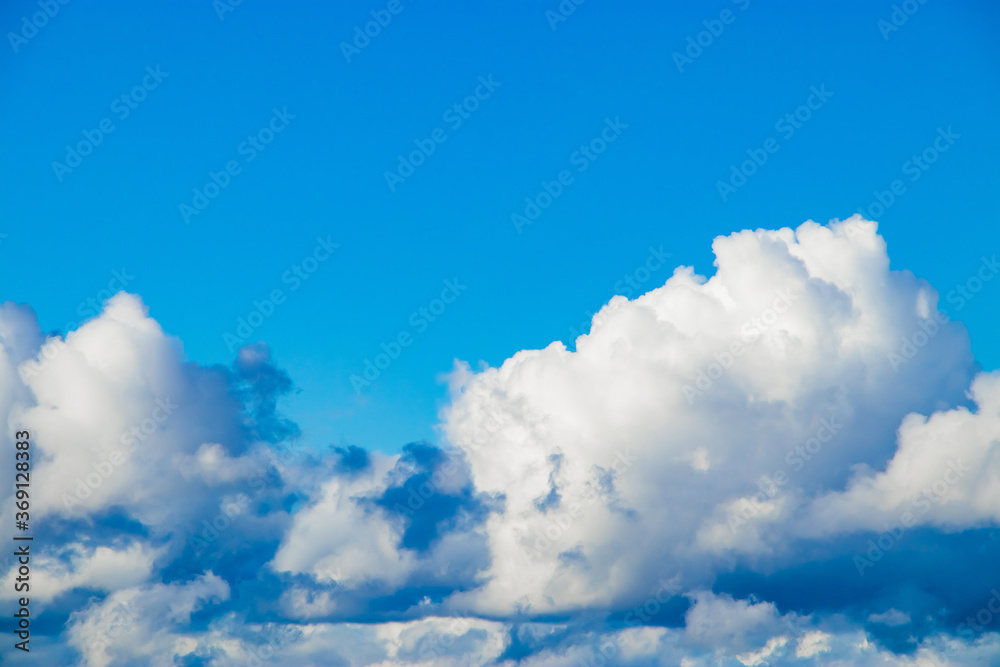White fluffy cumulus clouds against a blue sky. Top view from the plane. Background for design.