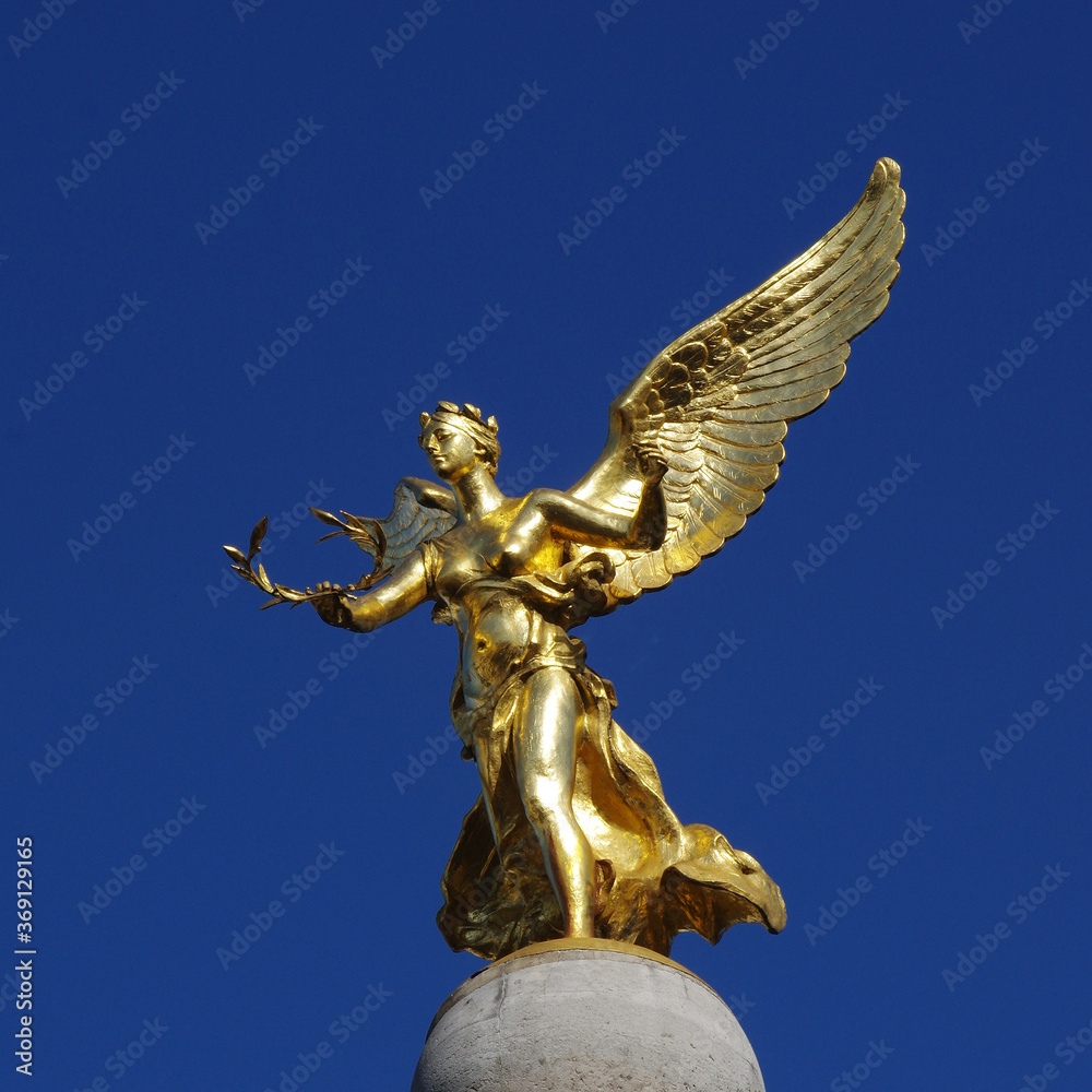 Golden statue of Nike with a wreath in her hands on a background of blue sky