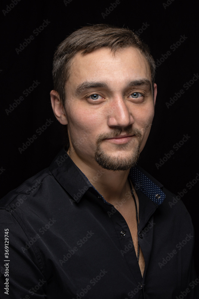 Closeup portrait of handsome man with a beard in black shirt. Isolated on black background