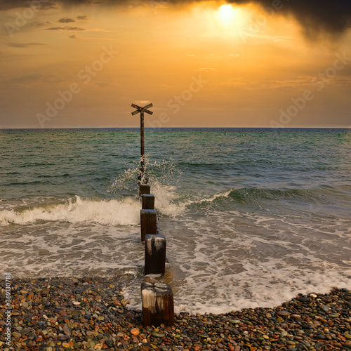 Canvastavla Wooden pillars and metal cross on Findhorn Beach, Moray Coast, Scotland with dramatic sunrise