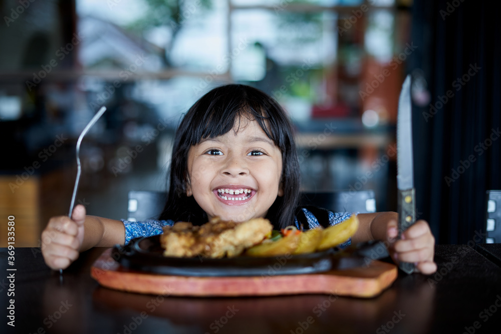 Smiling little girl eating steak at local restaurant Stock Photo ...