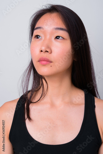 Portrait of young beautiful Asian woman against white background