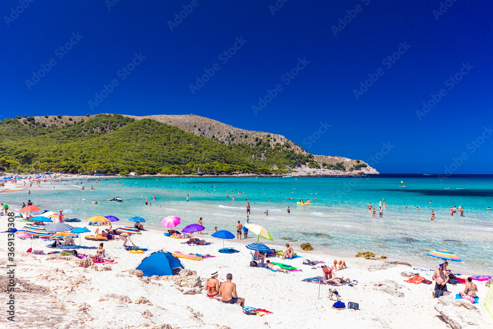 CALA AGULLA, MALLORCA, SPAIN - 21 July 2020: People enjoying summer on the popular beach on Mallorca, Balearic Islands. CALA AGULLA, MALLORCA, SPAIN - 21 July 2020: People enjoying summer on the popular beach on Mallorca, Balearic Islands.