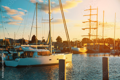 Boats in the port against the setting sun. Moored boats by the sea, sunset. The concept of sailing, spending time on a boat, sailboat.