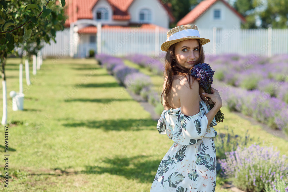 Charming pretty woman in straw hat with bouquet of lavender at lavender garden.