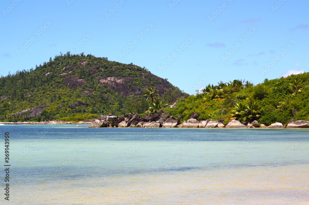Obraz premium Beautiful beach in Seychelles island, with turquoise blue water sea and white sand beach, granit rocks, mountain with green vegetation.