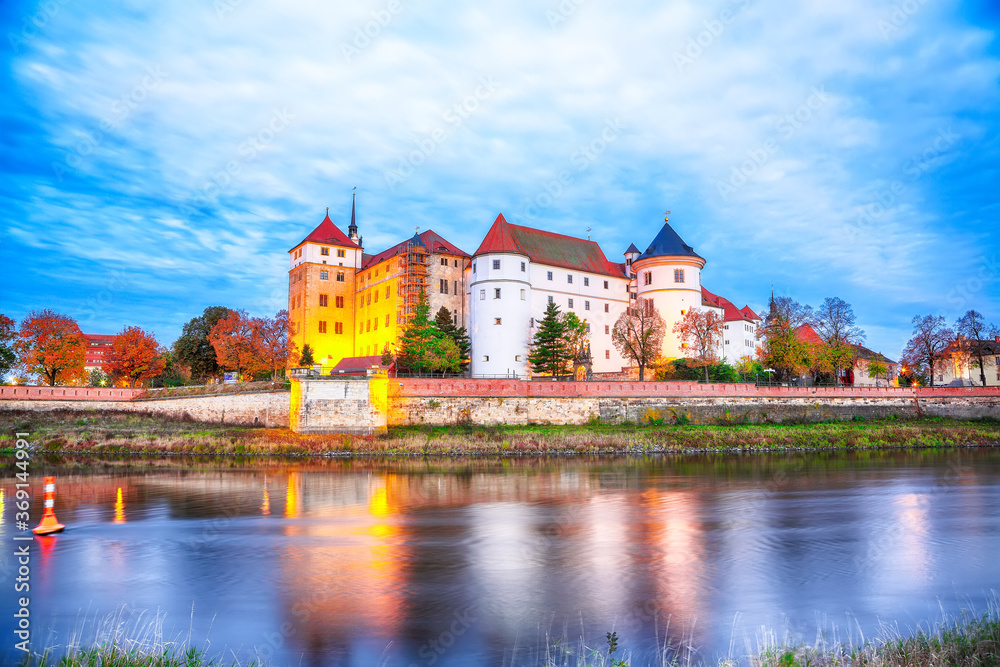 Picturesque morning view of Hartenfels castle on banks of the Elbe. Dramatic sunrise