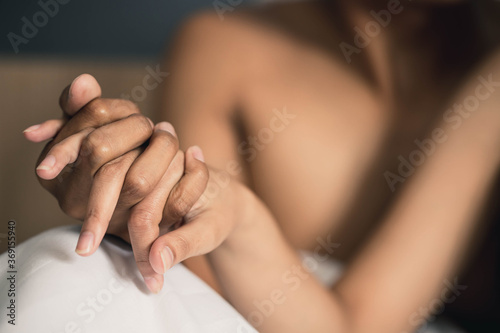A couple holding hands. the gentle touch of hands couple in love, which sitting on the bed. Woman and man in love sitting on couch two people holding hands.