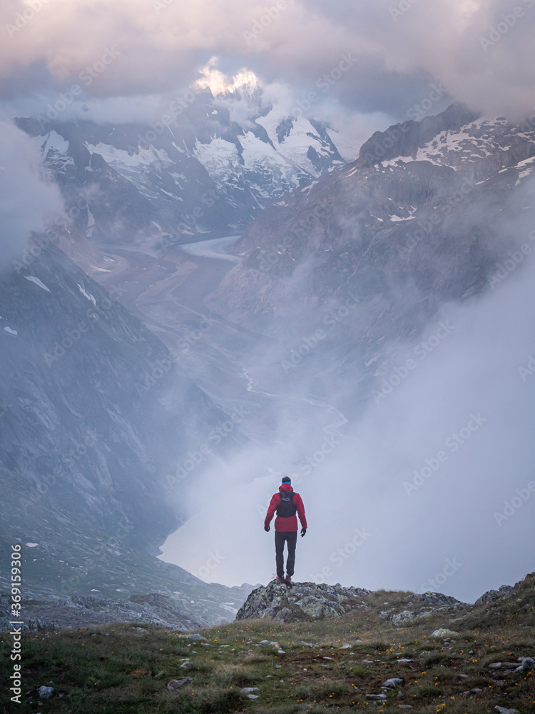 athlete standing in front of vast swiss alps athlete standing in front of vast swiss alps