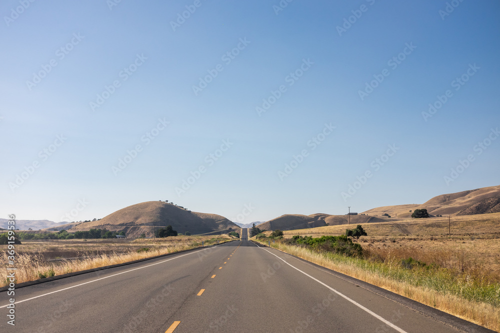 The wide open road through rolling desert hills The wide open road through rolling desert hills