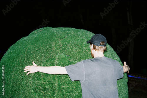 Anonymous man hugs a green Plastic mock of Planet Earth photo