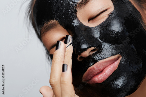 Woman using charcoal mask photo
