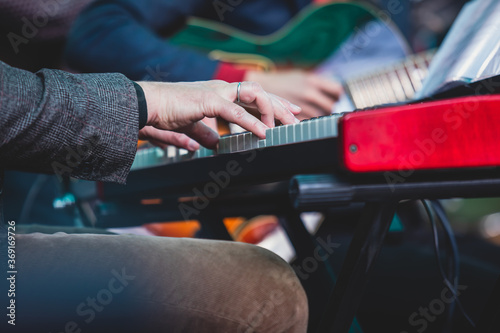 Concert view of a musical keyboard piano player during musical jazz band orchestra performing, keyboardist hands during concert, male pianist on stage, hands close up