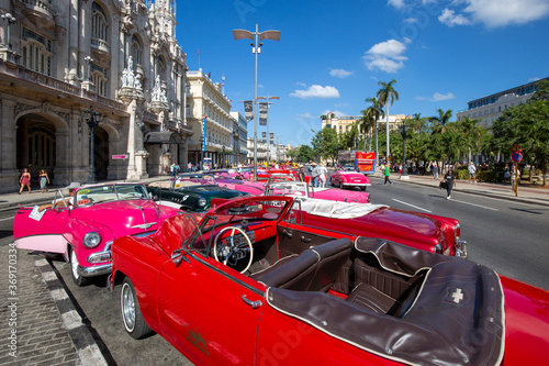 Havana, Cuba – 16 January, 2020: Famous colorful Taxis in Havana waiting for tourists to take a ride in a vintage car around major city attractions photo