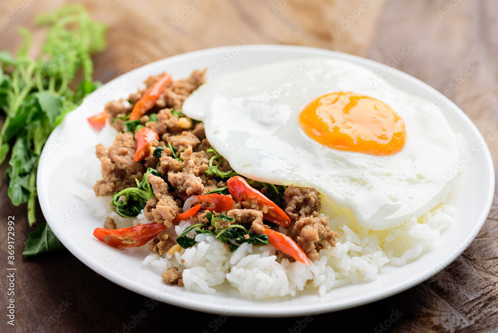 Thai food, stir-fried holy basil with minced pork and fried egg on top eating with cooked rice (Pad Kaprao Moo Kai Dao) Thai food, stir-fried holy basil with minced pork and fried egg on top eating with cooked rice (Pad Kaprao Moo Kai Dao)