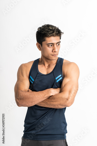 muscular man standing wearing gym clothes with crossed hands look sideways on an isolated background