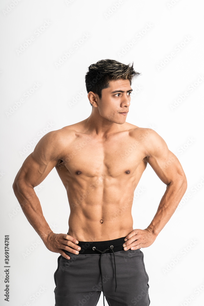 Sexy man show muscular bodies with two hands on waist stand facing forward and look side on isolated background Sexy man show muscular bodies with two hands on waist stand facing forward and look side on isolated background