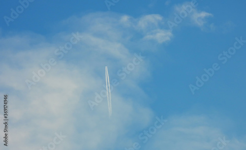 Airplane flying in the clear blue sky and contrail against, Engine exhaust contrails forming behind, Jet contrails or trails over blue sky and clouds.