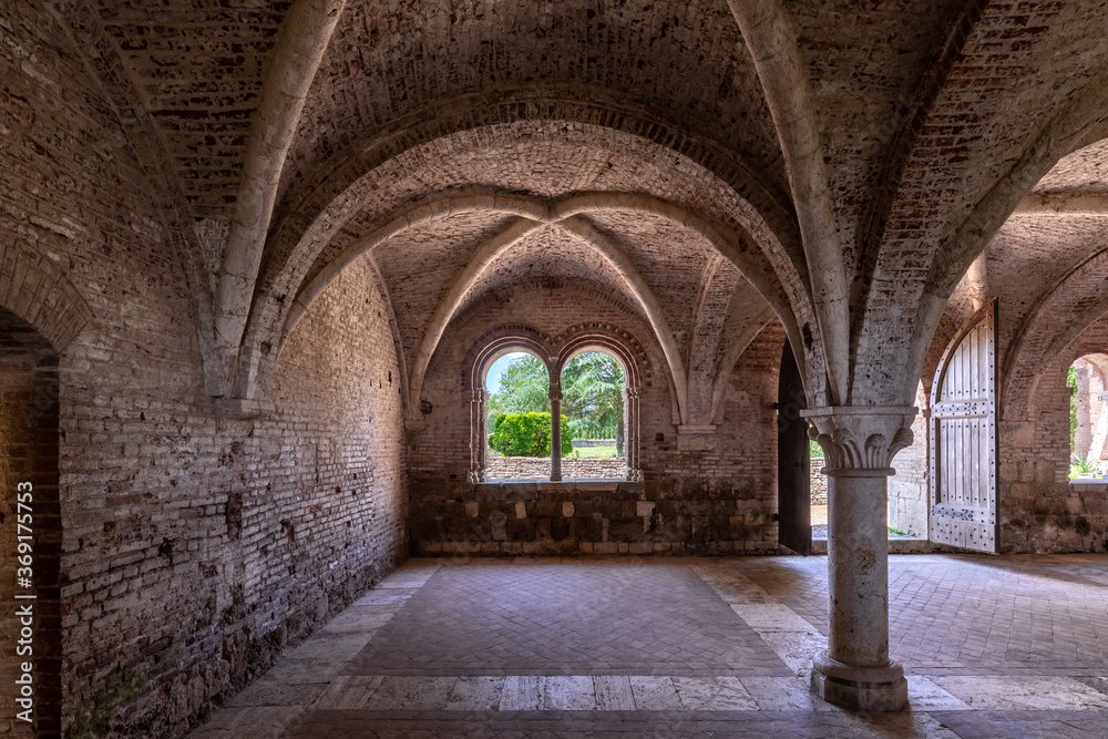 Interior of an ancient italian monastery, with a cross vaulted hall and a mullioned window