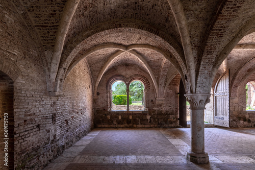 Interior of an ancient italian monastery, with a cross vaulted hall and a mullioned window