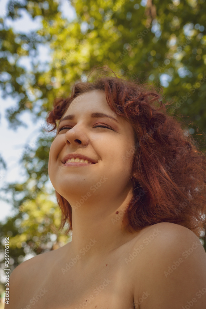 red-haired curly-haired girl in a summer dress posing in the village . High quality photo red-haired curly-haired girl in a summer dress posing in the village . High quality photo