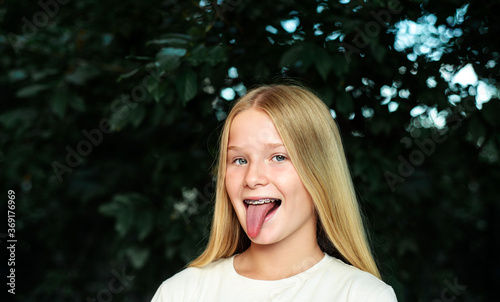 Smiling girl with orthodontic braces and sticking her tongue out