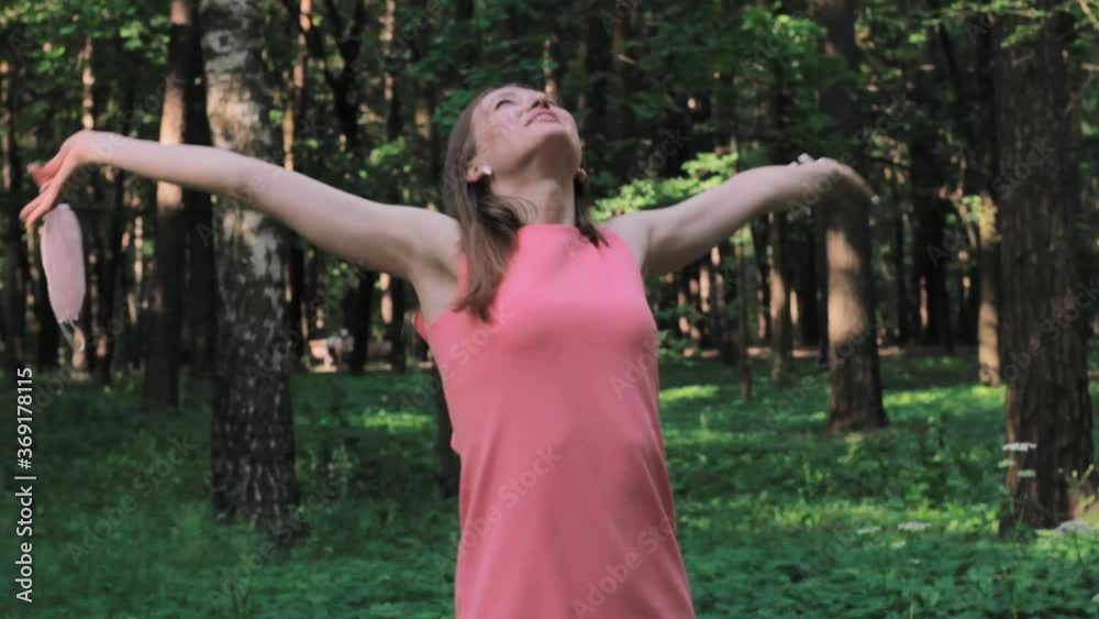 A young woman in a pink dress in a Park, removes a medical mask, breathes fresh air, rejoices and dances. Quarantine is over concept. A young woman in a pink dress in a Park, removes a medical mask, breathes fresh air, rejoices and dances. Quarantine is over concept.