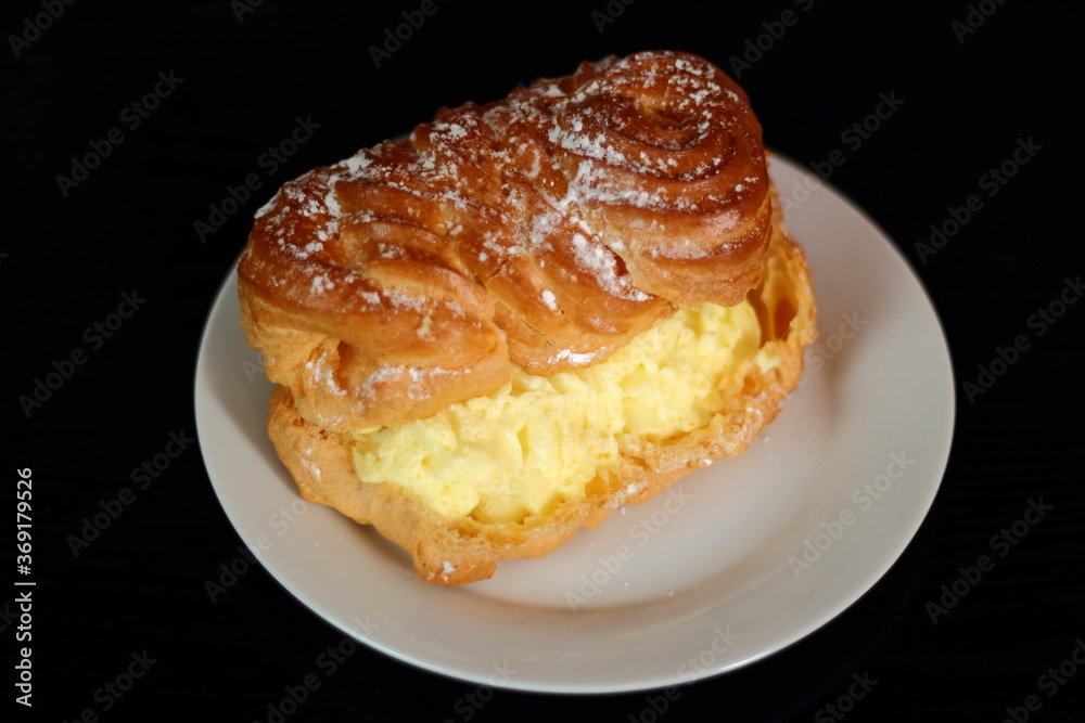 Eclair filled with pastry cream (custard) and topped with icing sugar Eclair filled with pastry cream (custard) and topped with icing sugar