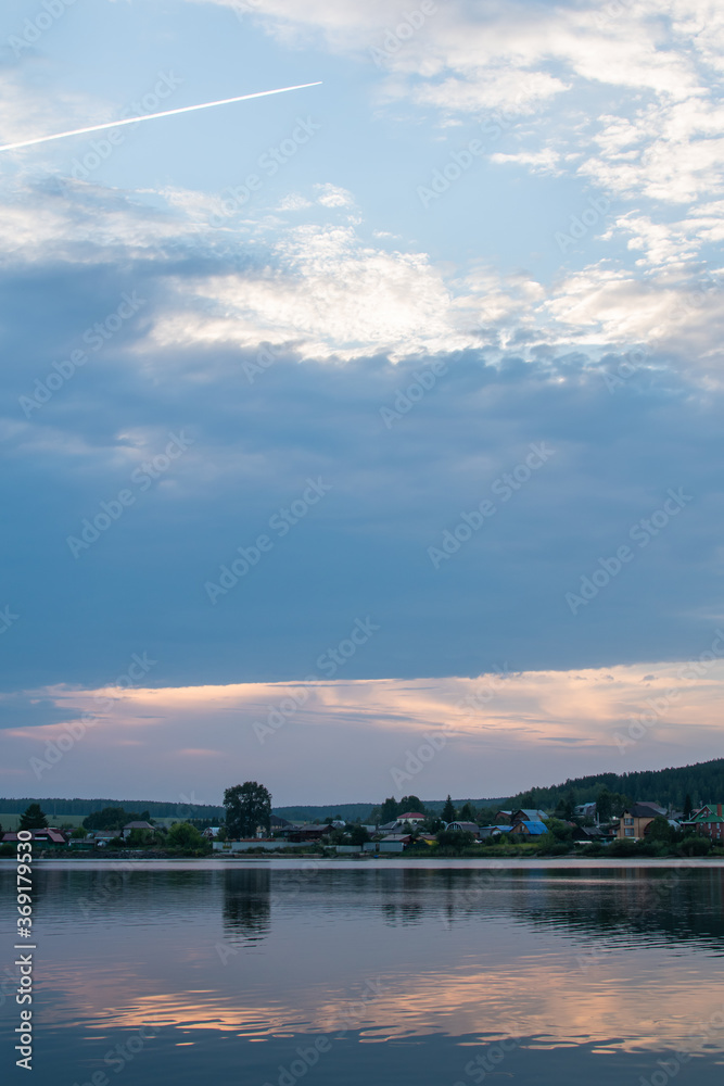 Summer twilight landscape. River with the reflection in water. Beautiful view. Russia