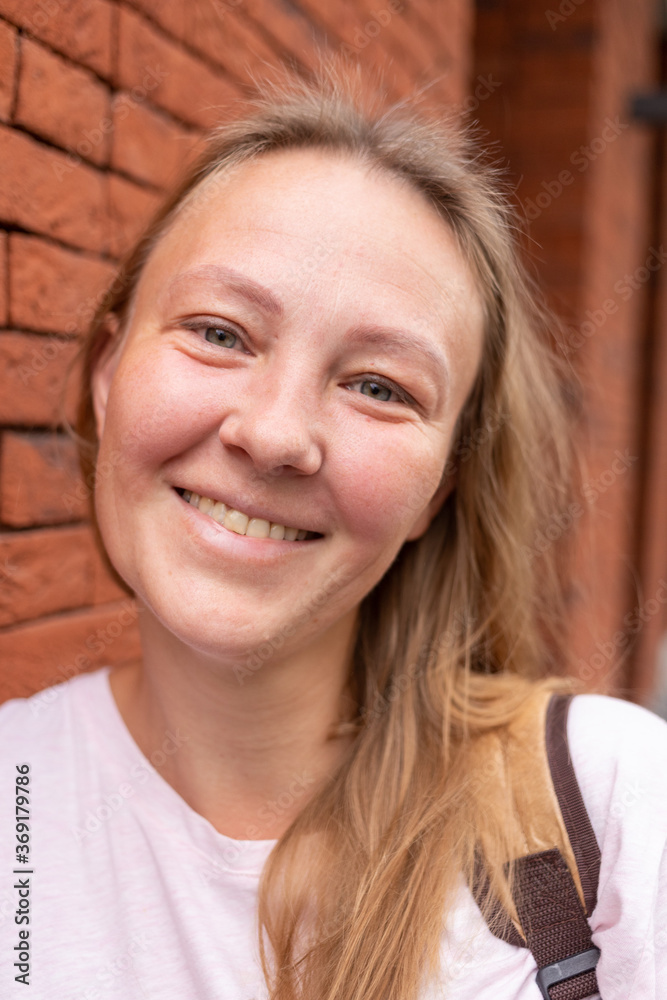 a beautiful smiling girl in a white t-shirt and jeans poses on the streets of the city. she has long hair and no makeup. the architecture of the old city is a backdrop around it. High quality photo a beautiful smiling girl in a white t-shirt and jeans poses on the streets of the city. she has long hair and no makeup. the architecture of the old city is a backdrop around it. High quality photo